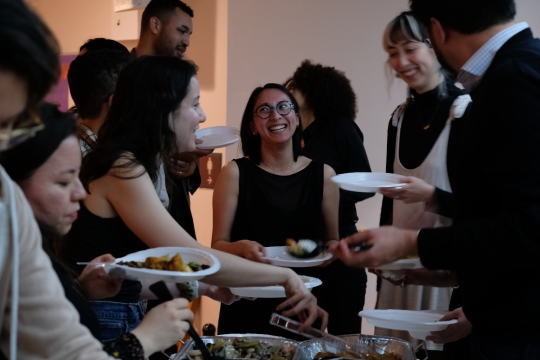 A group of people attending LUNAR's Passover seder standing around a table scooping food onto their plates.